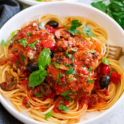 Chicken cacciatore shown served over pasta in a white bowl.