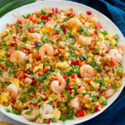 Large white serving bowl with shrimp fried rice set on a marble surface.