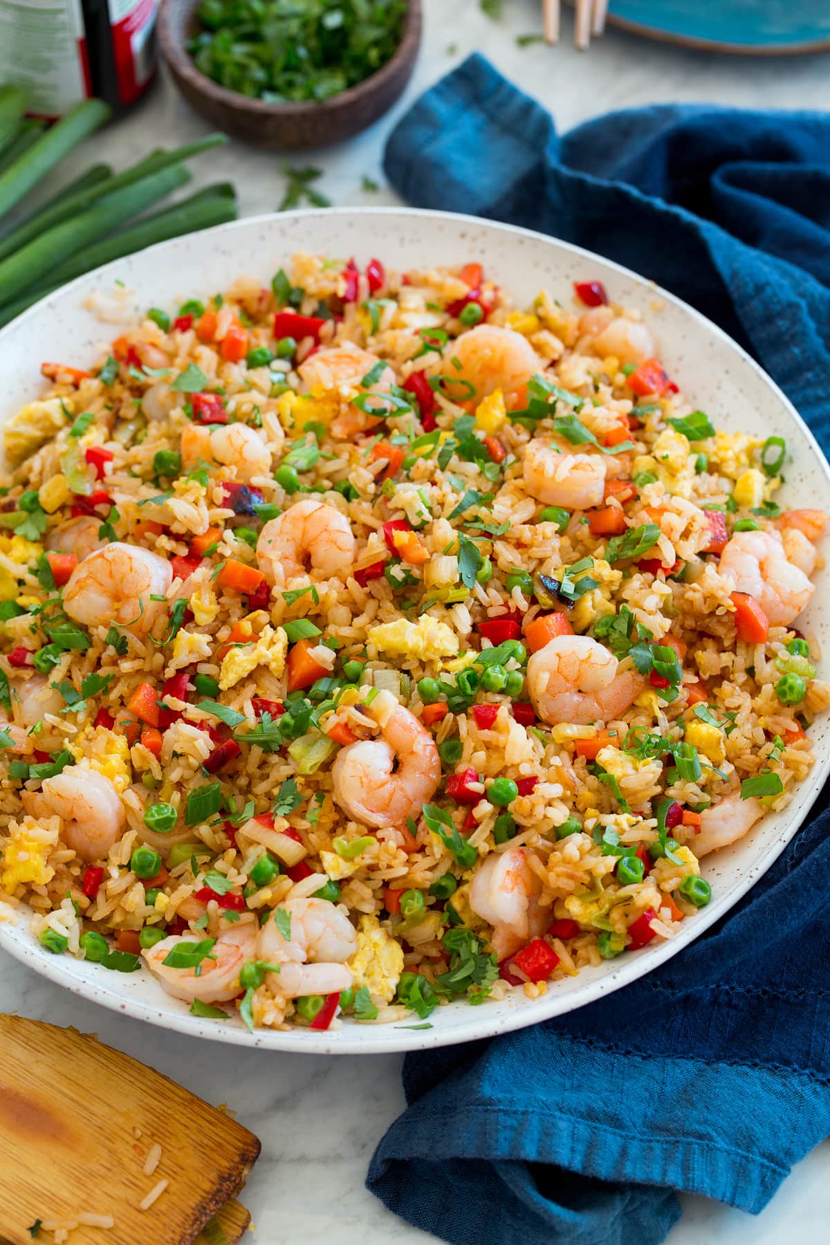 Large white serving bowl with shrimp fried rice set on a marble surface.