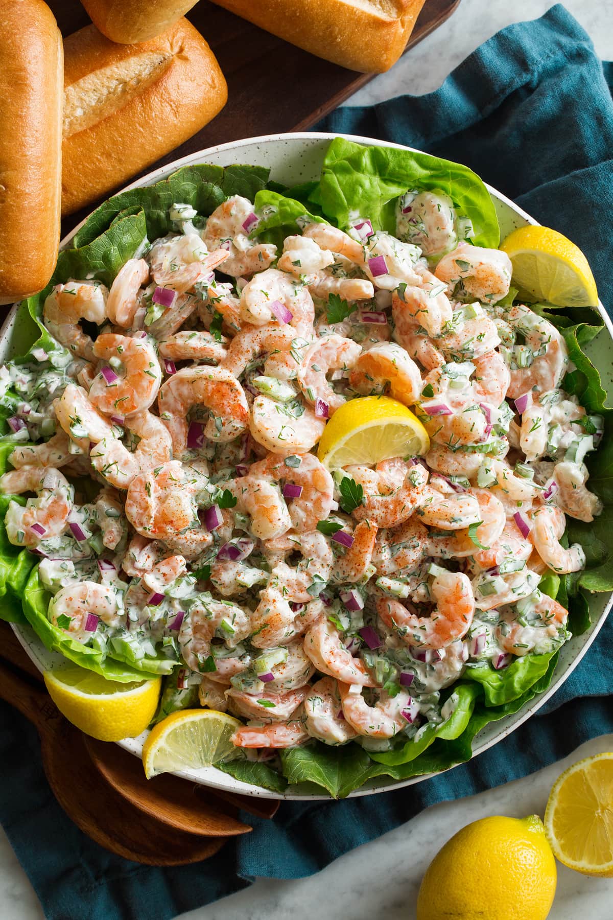 Shrimp salad with lemons and lettuce in a serving bowl.