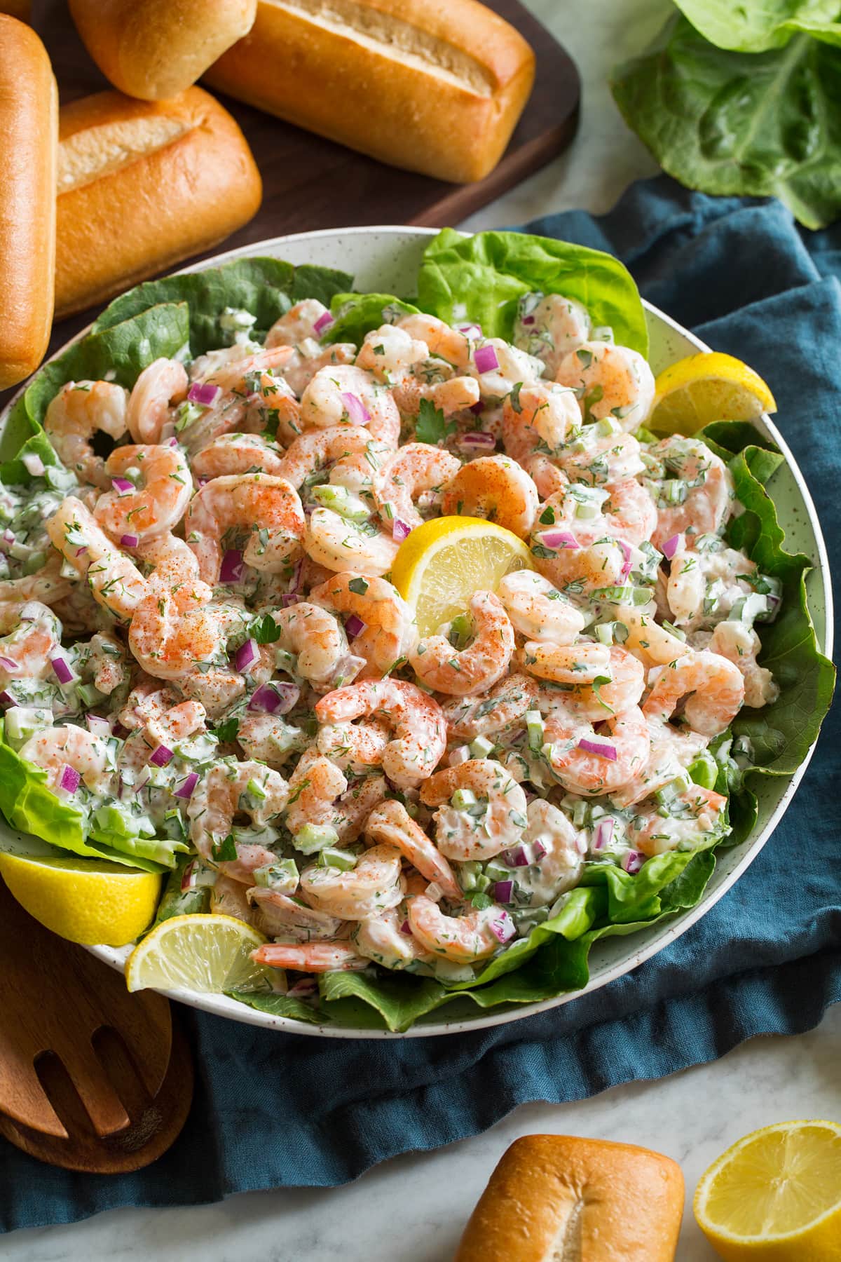 Shrimp salad with lemons and lettuce in a serving bowl.