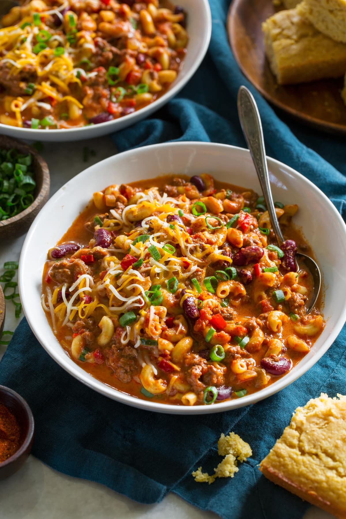 Single serving of chili mac in a white bowl over a blue cloth.