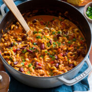 Chili mac in a large pot with a wooden spoon scooping mixture.