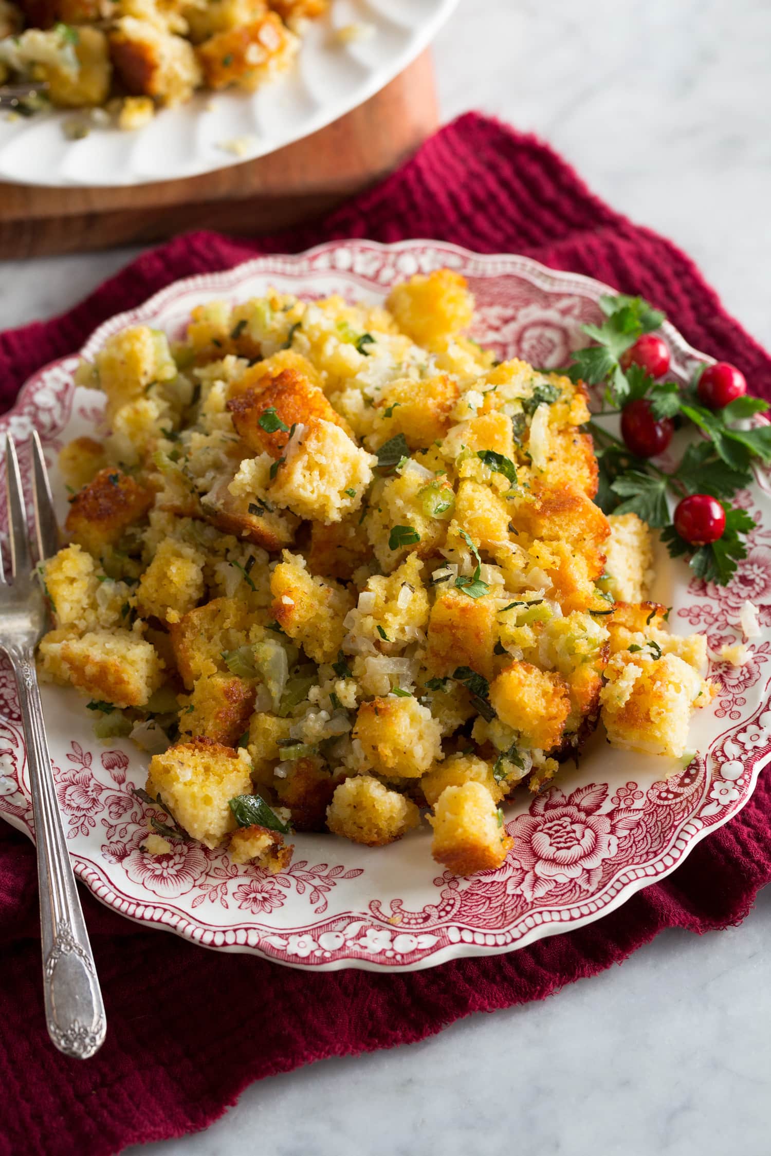 Single serving of cornbread stuffing on a small antique white and red serving plate.