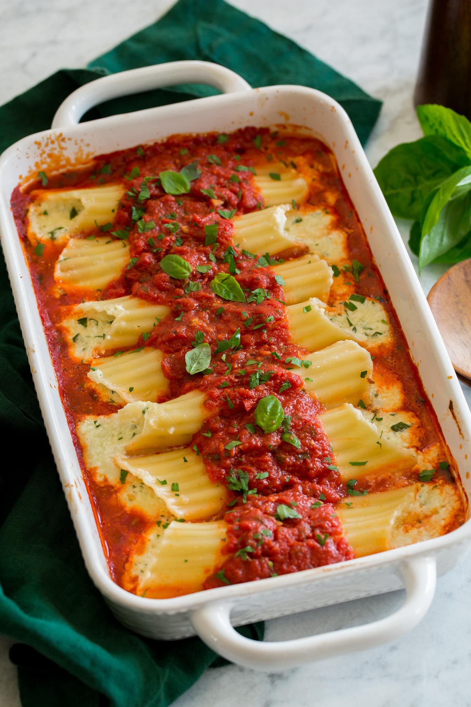 Homemade manicotti stuffed with cheese in a baking dish with marinara sauce.