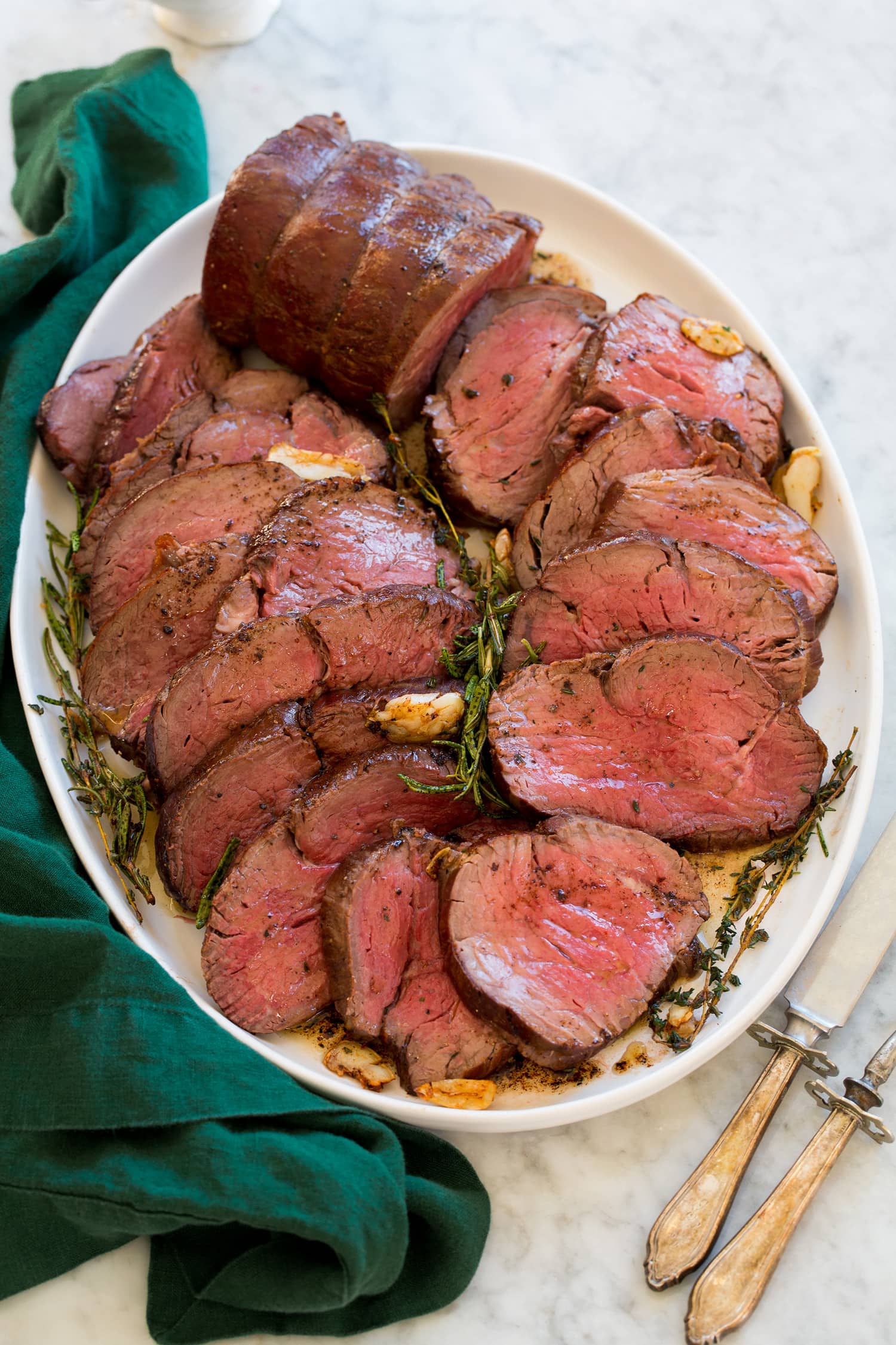 Platter with beef tenderloin slices cooked medium rare overlapping on each other.