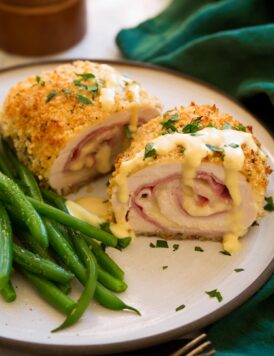 Chicken Cordon Bleu shown sliced in half with sauce on top. Green beans shown to the side.