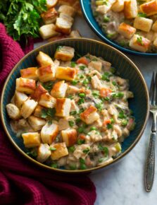 Chicken pot pie mixture in a blue bowl topped with puff pastry bites.