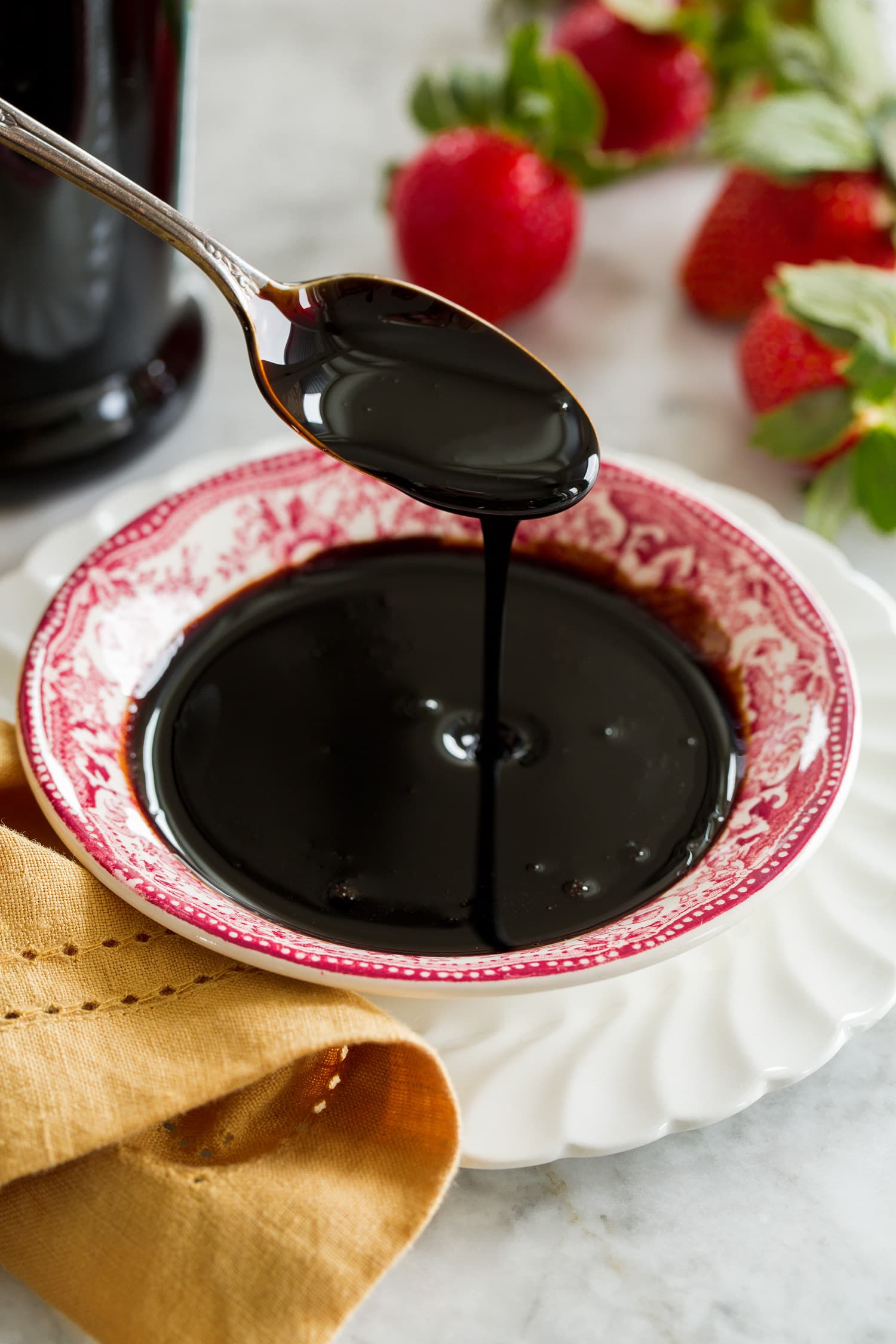 Balsamic glaze drizzled from a spoon into a small dish.