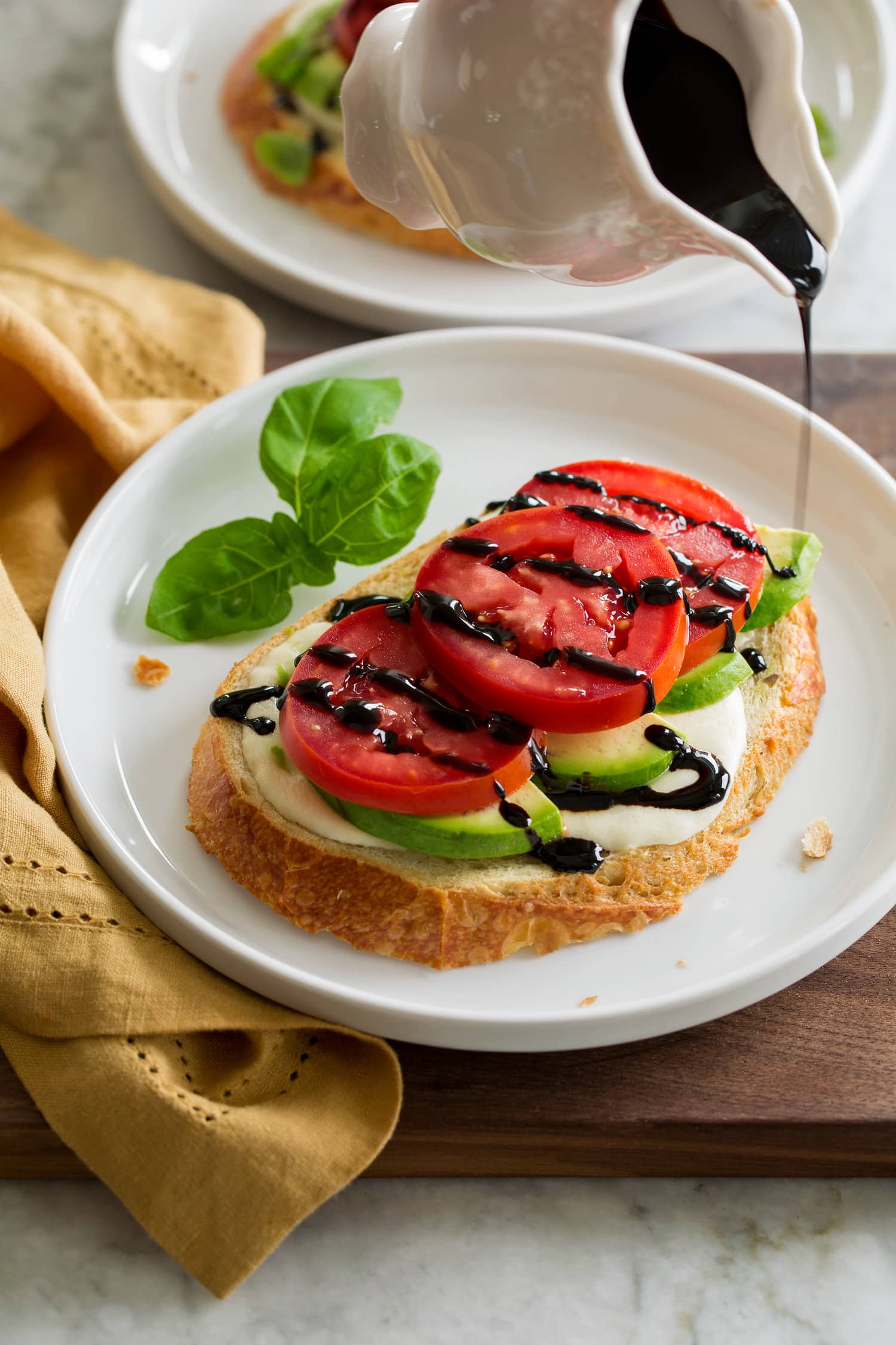 Homemade balsamic glaze being drizzled over avocado caprese toast.