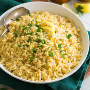 Bowl of lemon orzo set over a green cloth and a wooden tray.