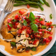 Bruschetta Chicken served with balsamic glaze and a side of toasted baguette and asparagus.