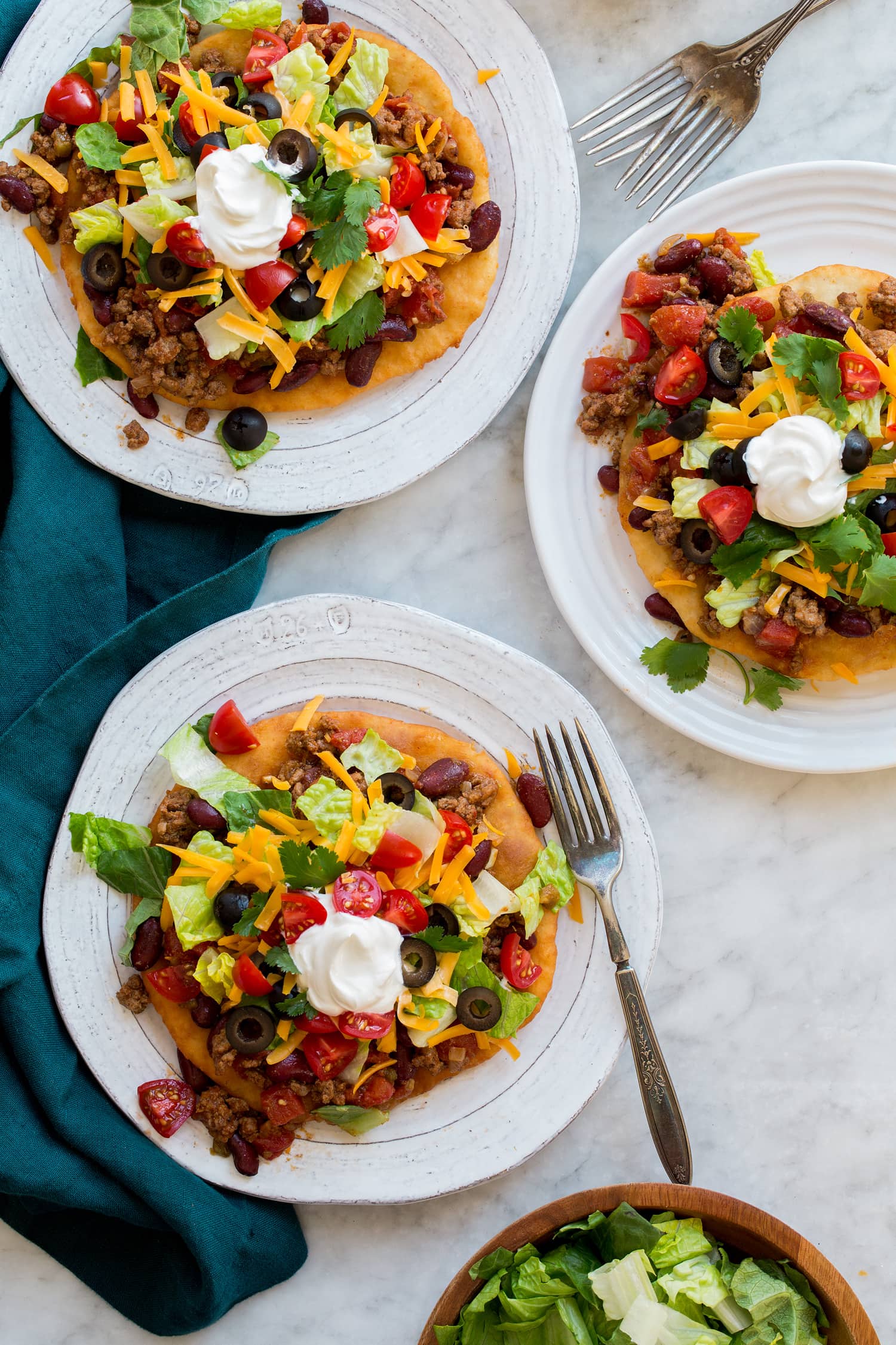 Three navajo tacos shown on plates from above.