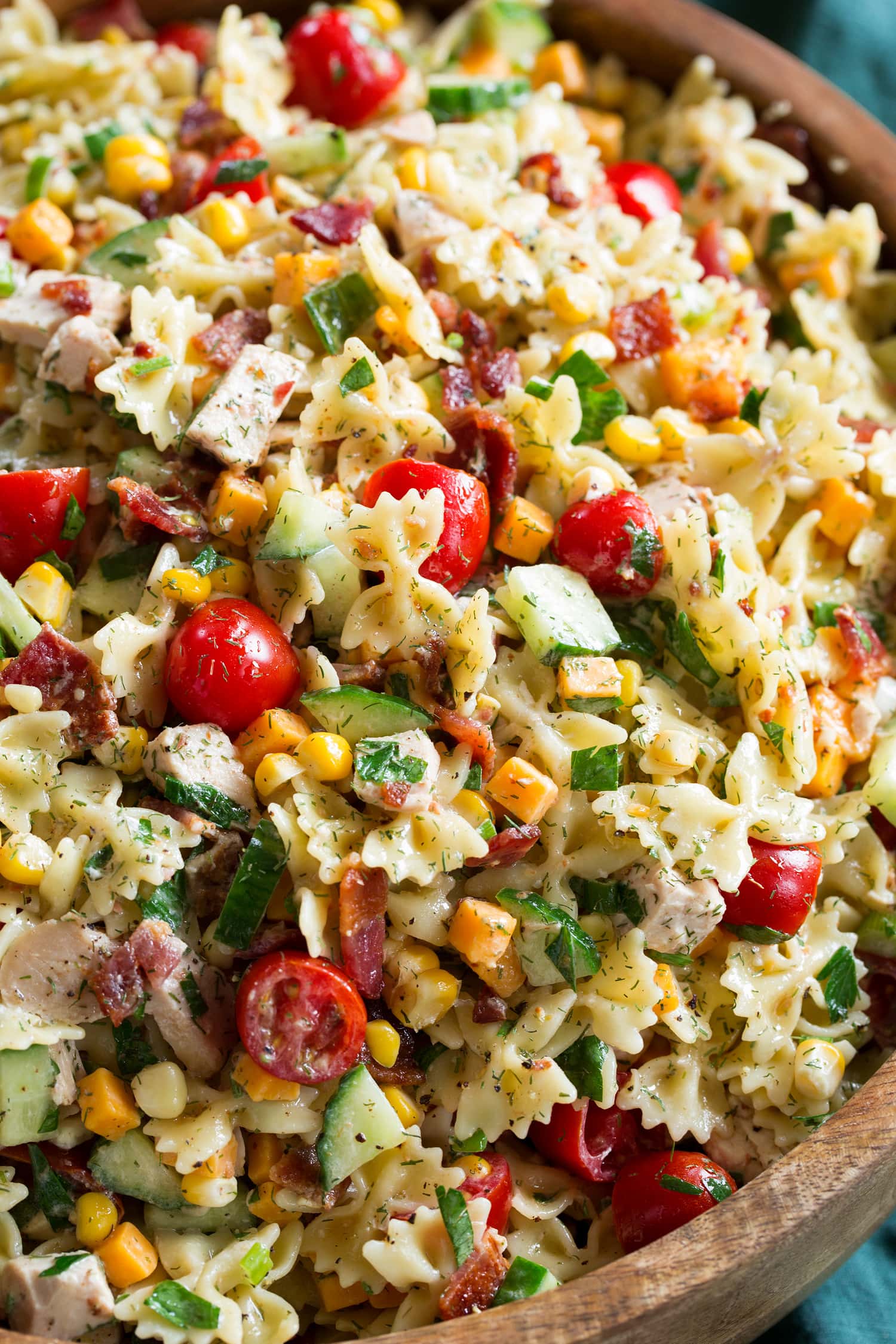 Close up photo of club chicken pasta salad in a wooden bowl.