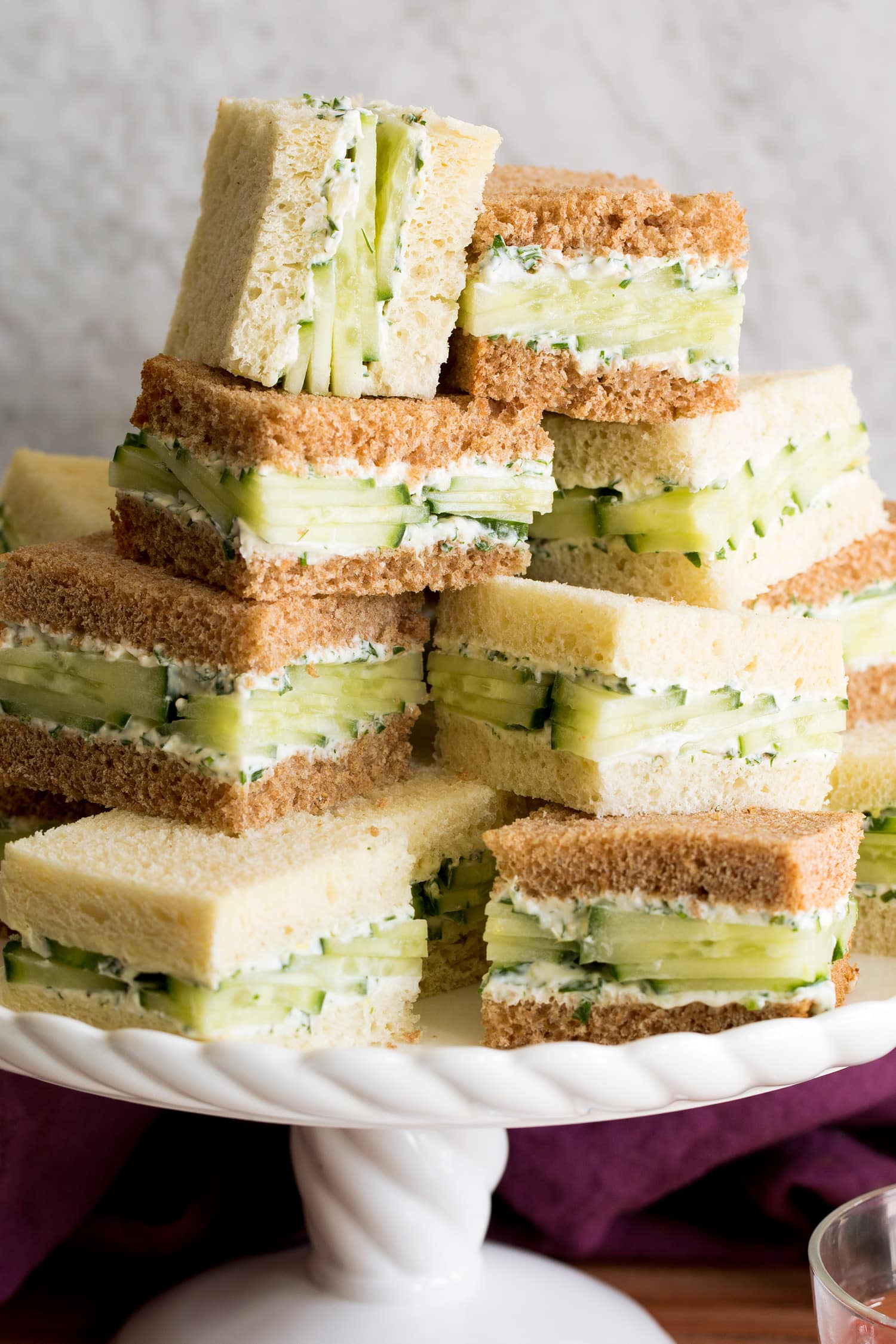 Close up photo of stack of cucumber sandwiches on a cake stand.