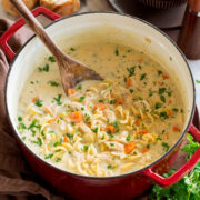 Pot full of homemade creamy chicken noodle soup served with a side of bread.