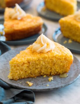 Slice of southern cornbread shown on a plate, it's topped with a swirl of honey butter.