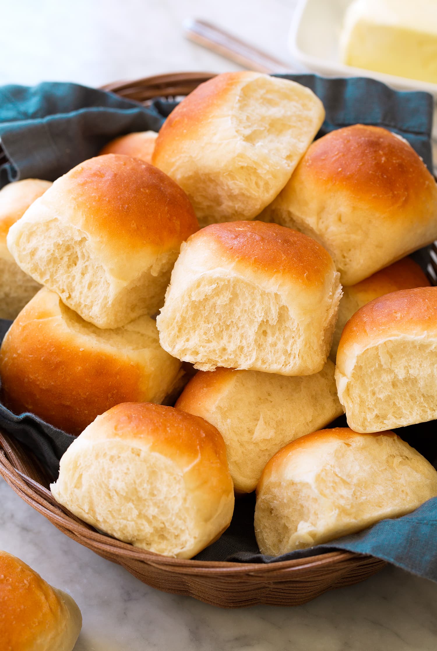 Easy Homemade Dinner Rolls in a bread basket with a blue cloth.