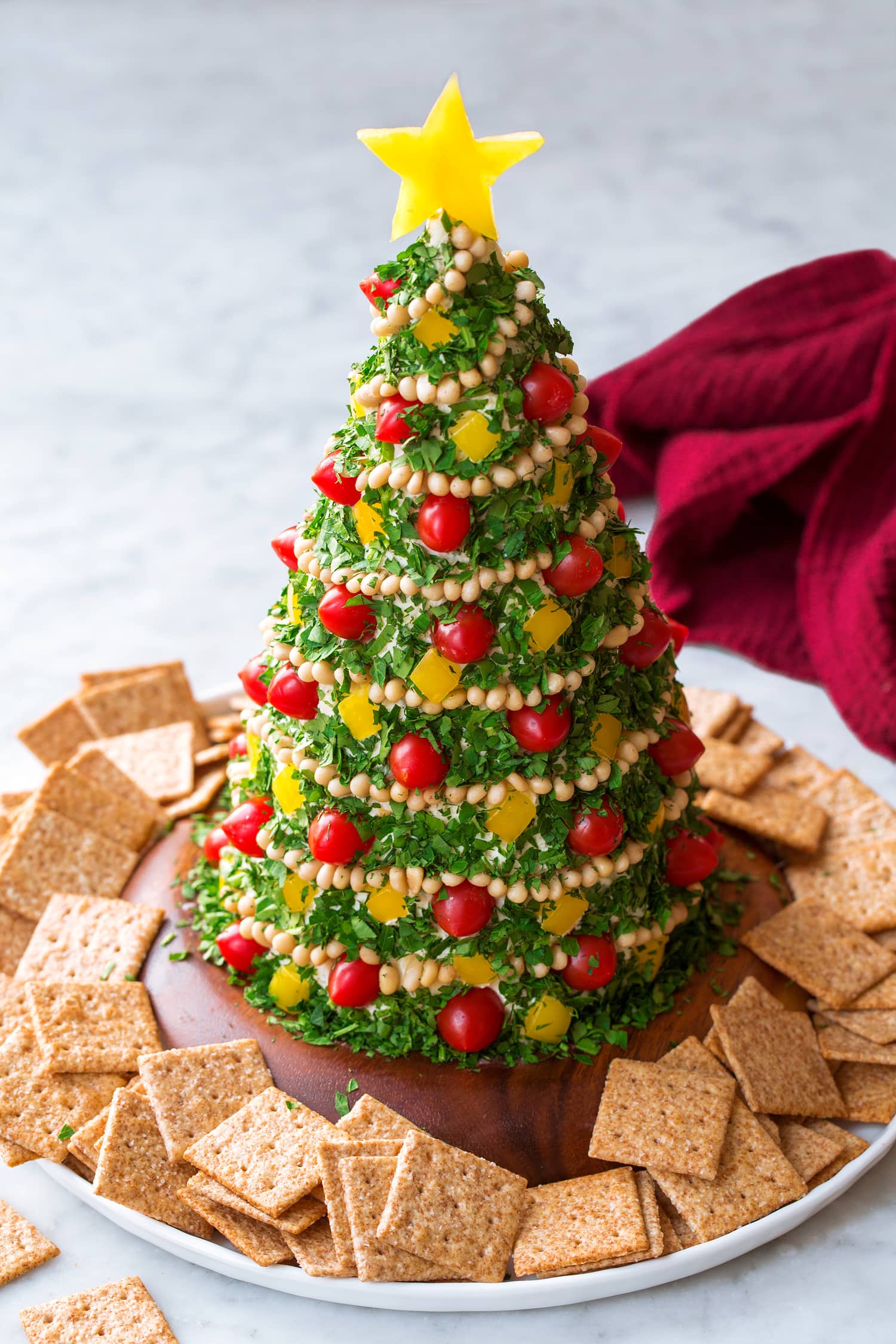 Christmas Tree Cheese Ball made with white cheddar, cream cheese, and covered in parsley, tomatoes, pine nuts and bell peppers.