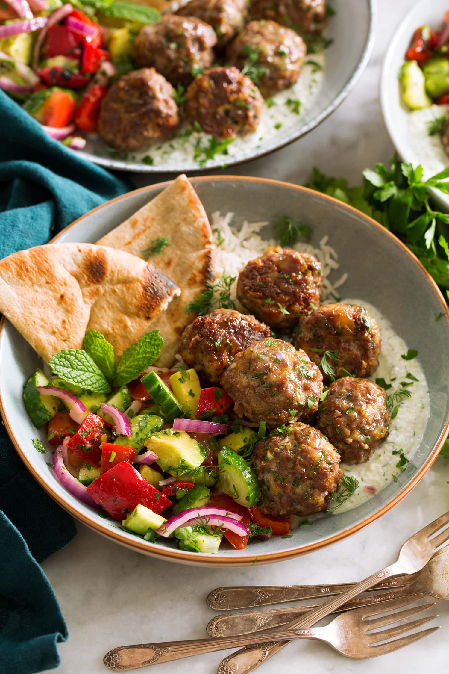 Greek meatballs shown served with tzatziki and greek salad.