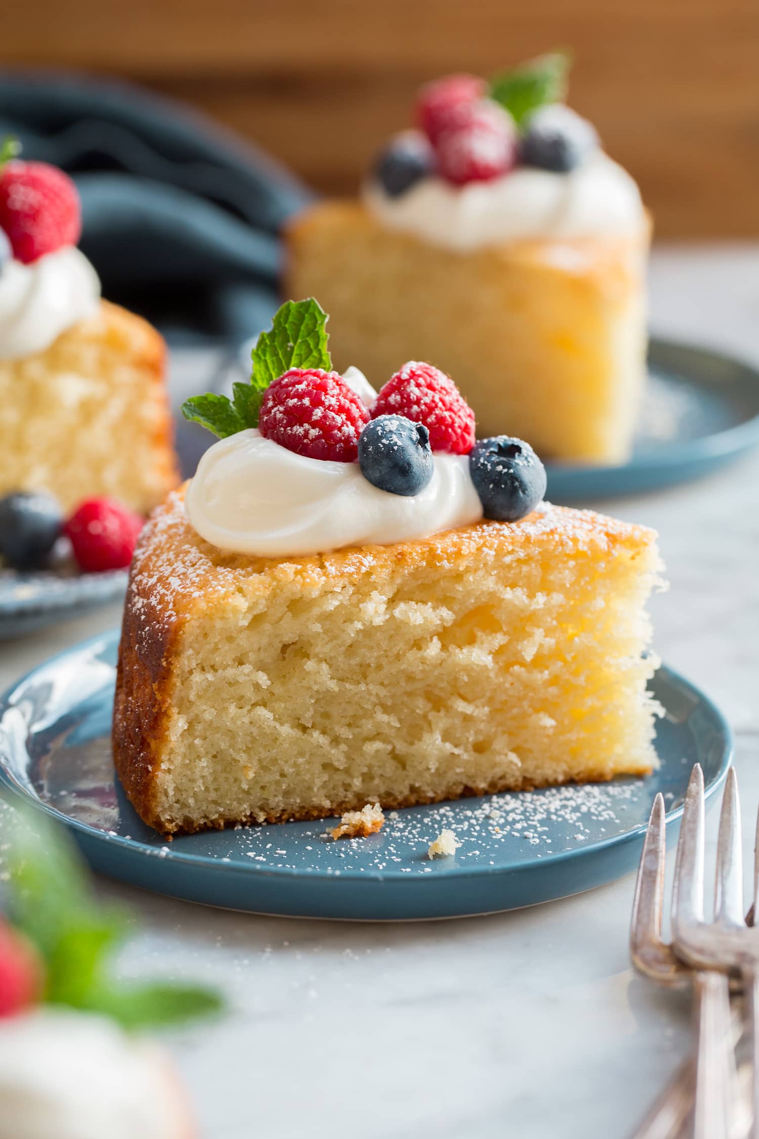 Slice of yogurt cake shown close up with yogurt and berries on top.