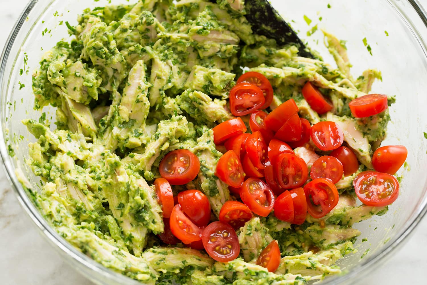 Adding tomatoes to chicken salad.