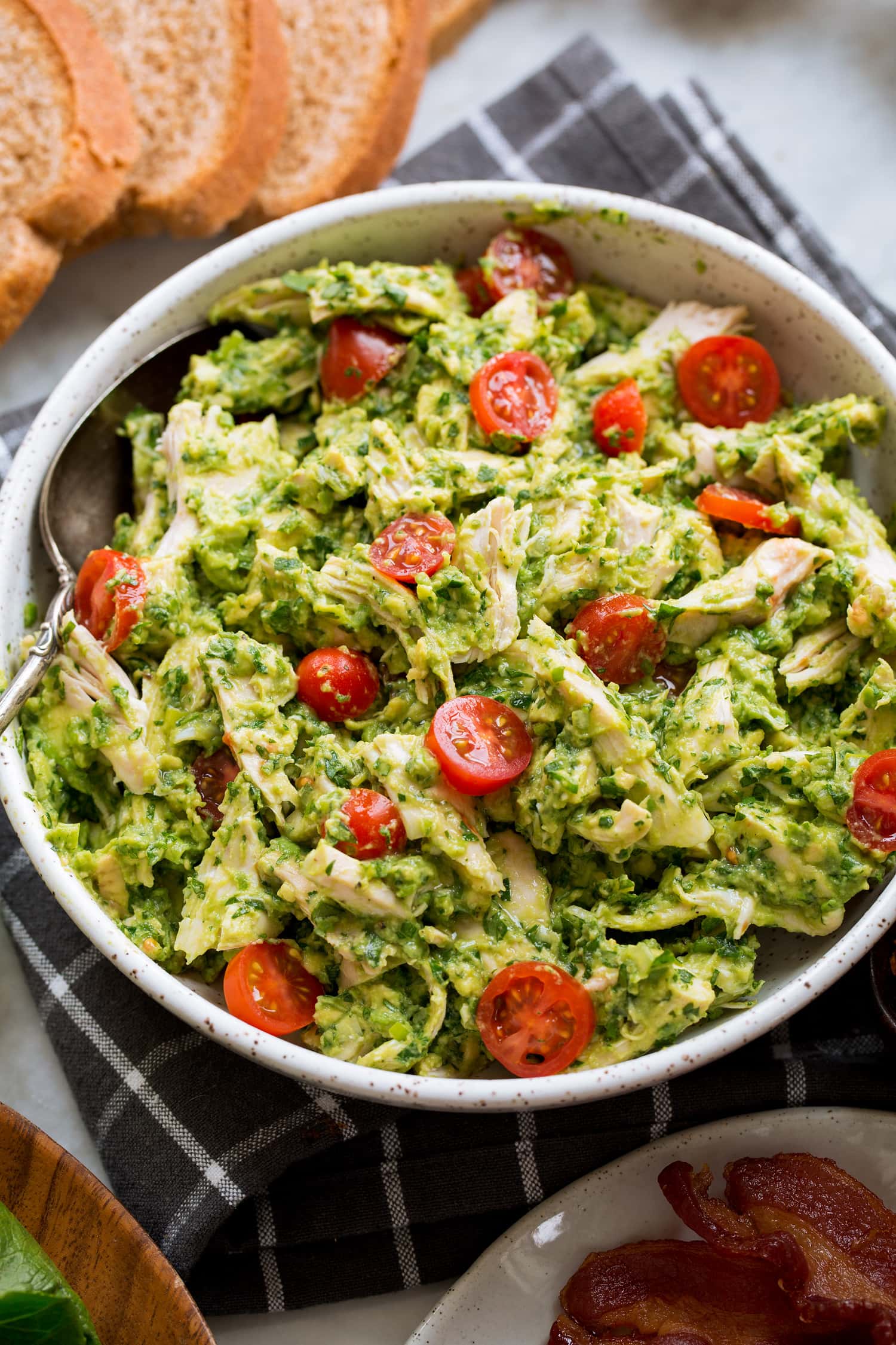 Avocado chicken salad mixture in a bowl with tomatoes.