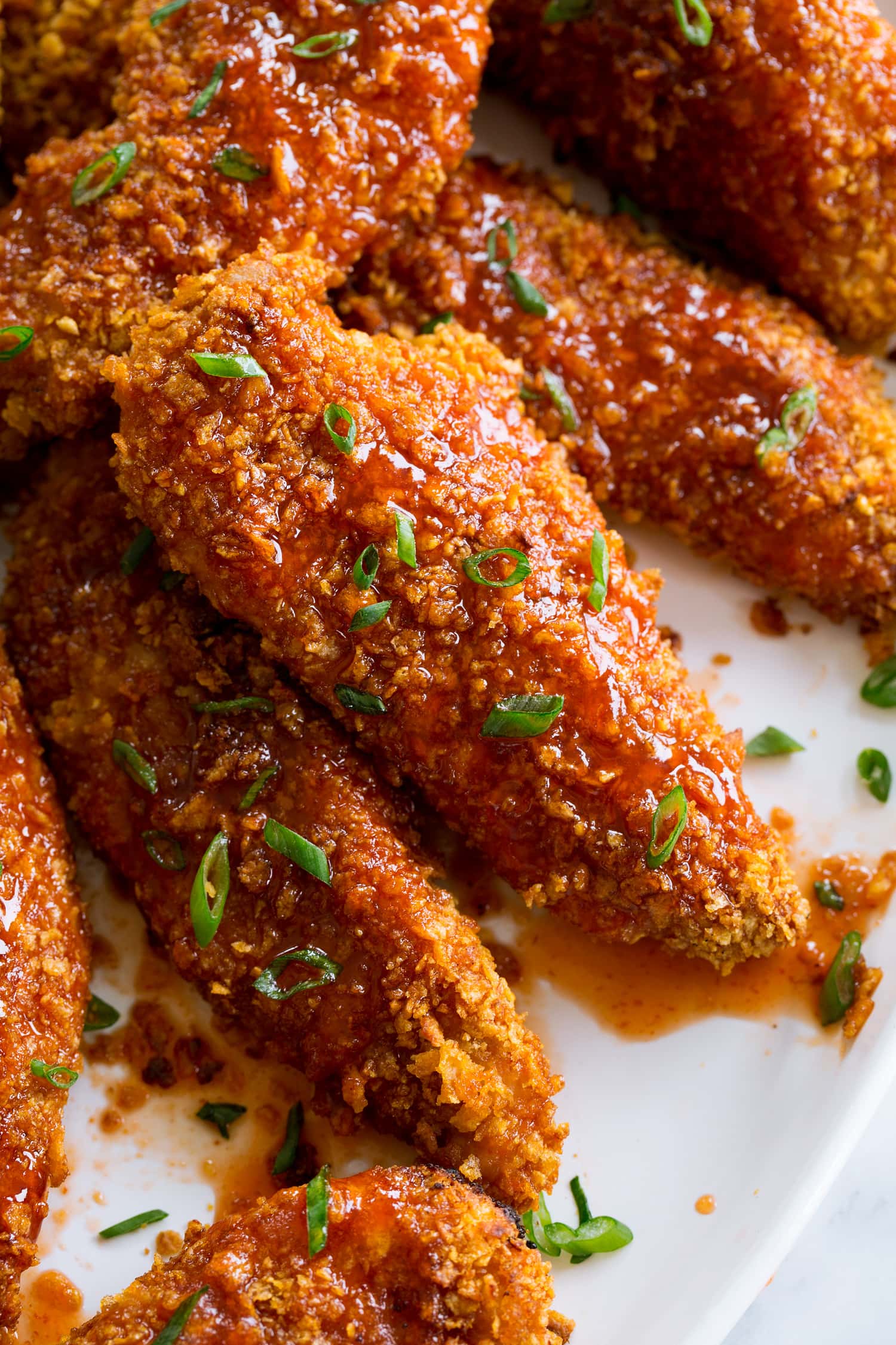 Close up photo of chicken strip coated in hot honey sauce.