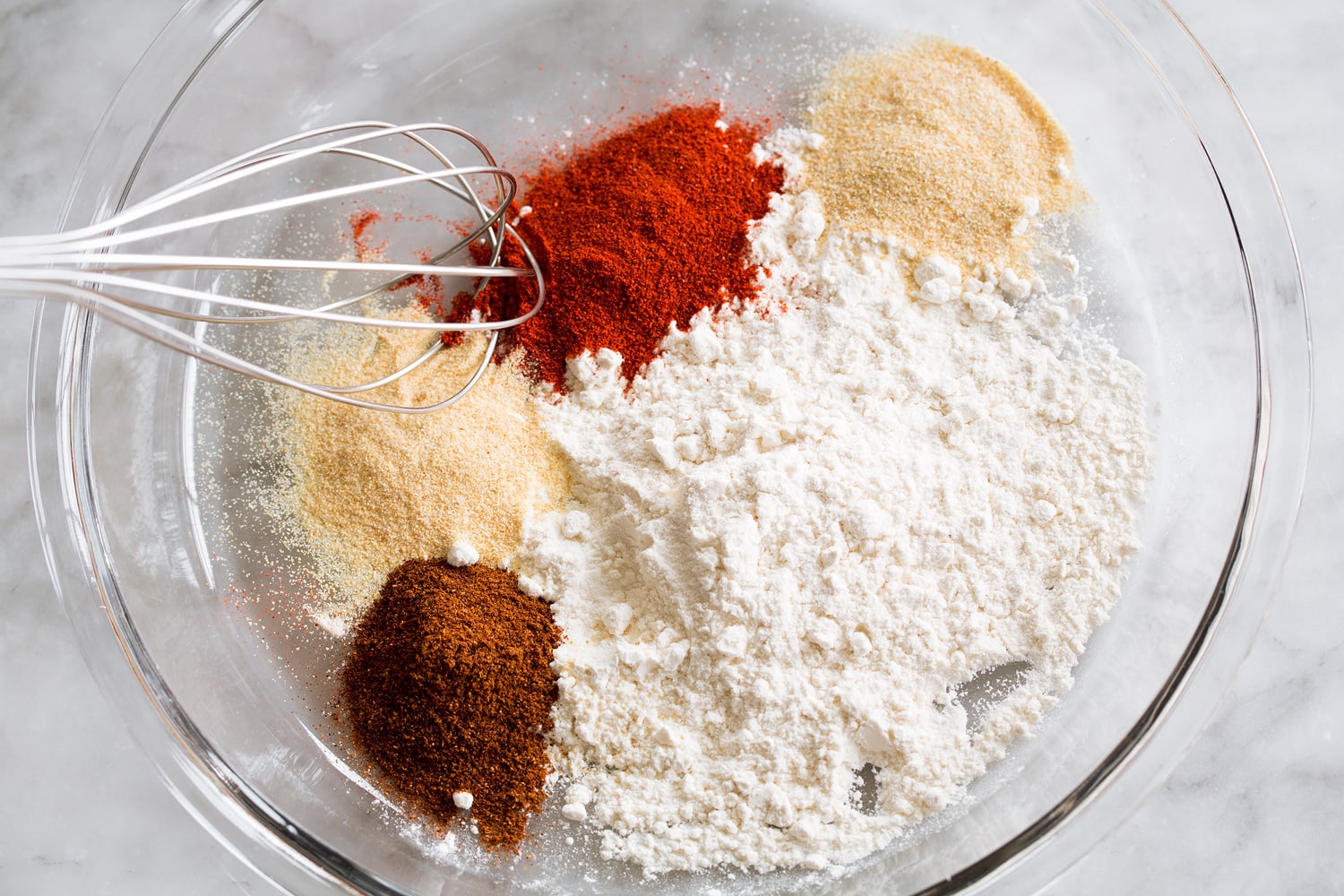 Mixing flour and spices in a shallow dish for dredging chicken.