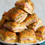 Stack of ham and cheese sliders in a pyramid shape.