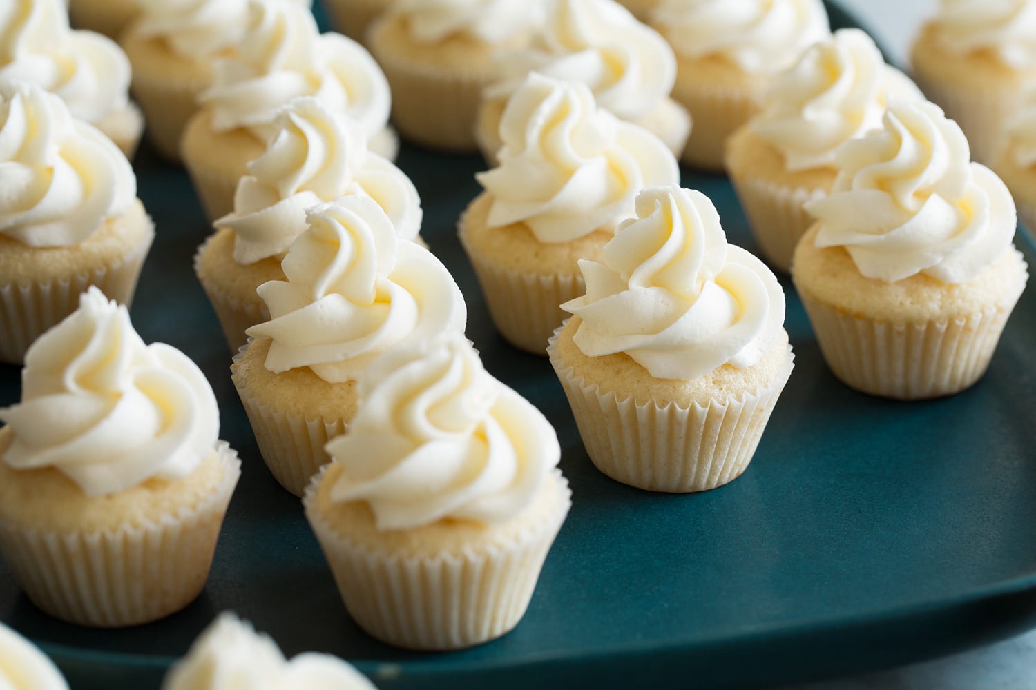 Mini vanilla cupcakes completed with frosting on top.