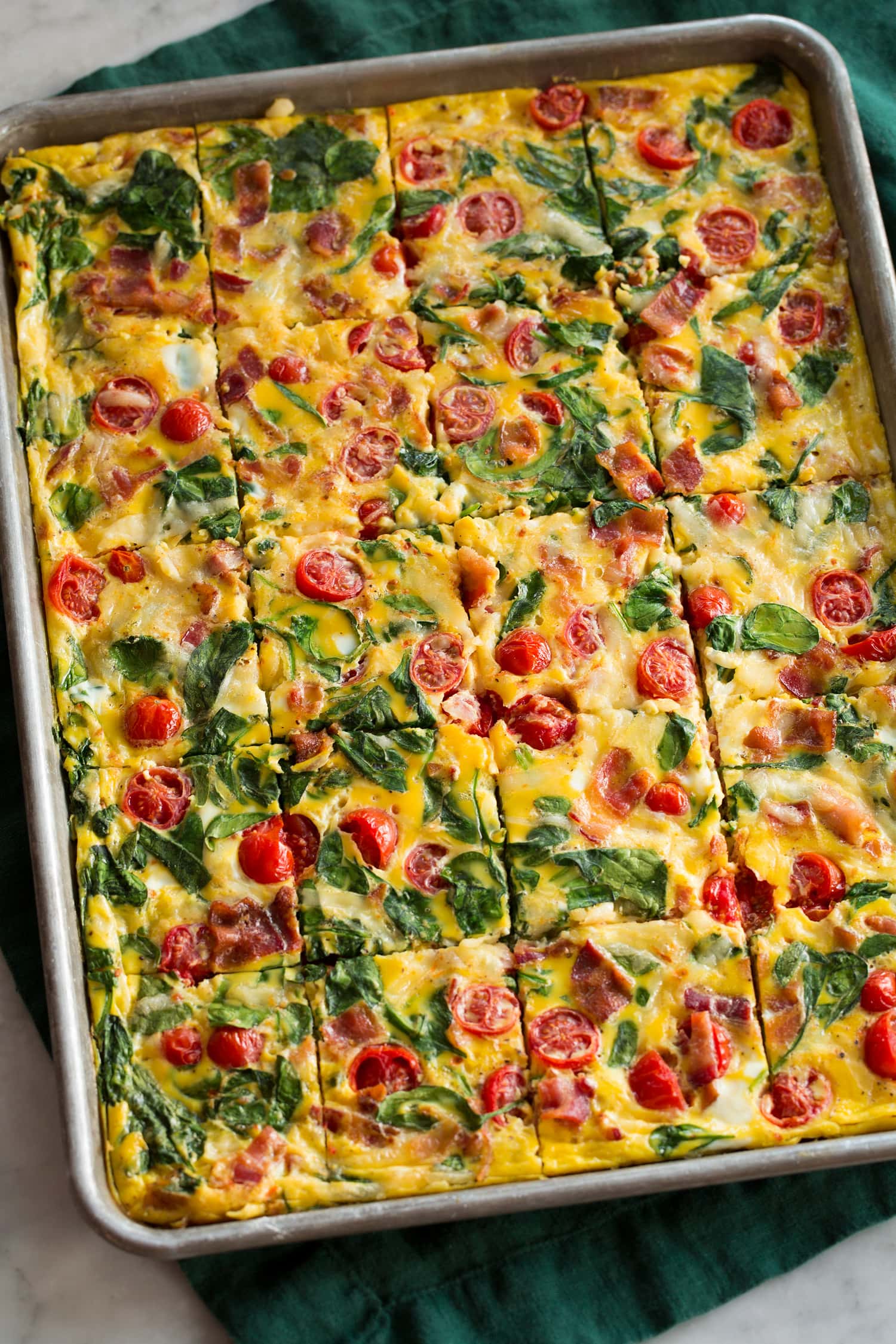 Bacon, tomato, spinach eggs in a baking sheet.