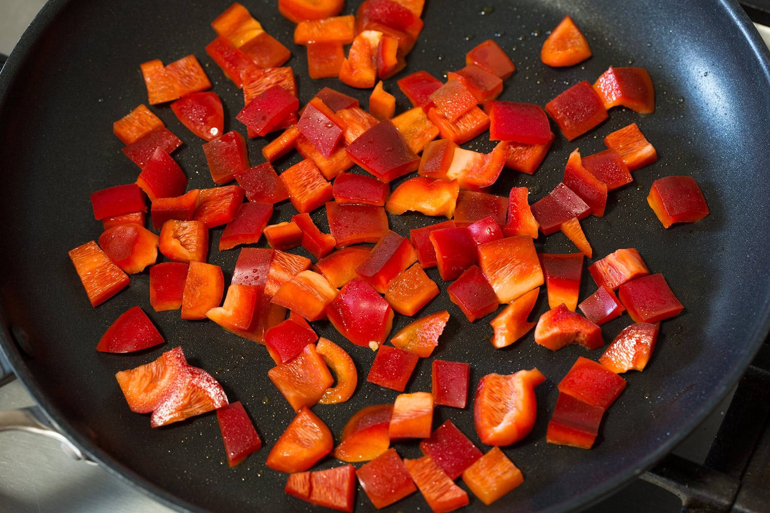 Sautéing bell pepper in a dark skillet.