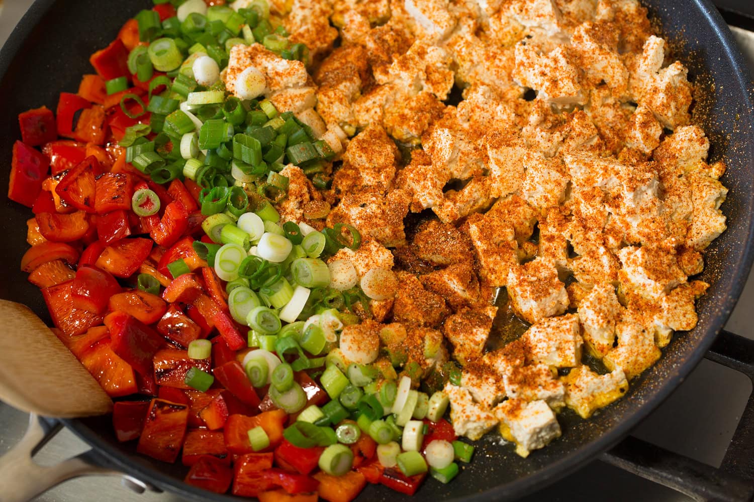 Adding tofu, green onions and seasonings to skillet.