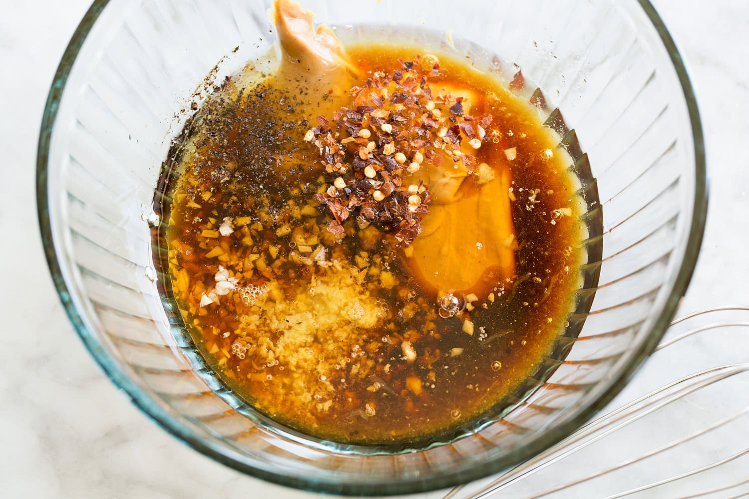 Ingredients for Chinese chicken salad dressing in a glass mixing bowl shown before mixing.