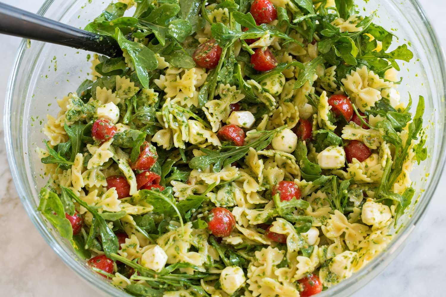 Pesto pasta salad shown after mixing.