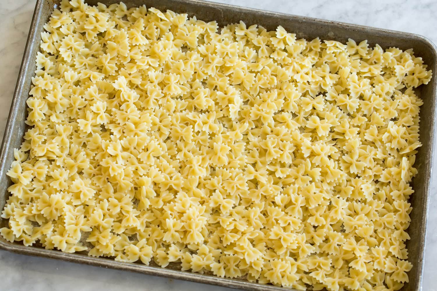 Pasta cooling on a cookie sheet.