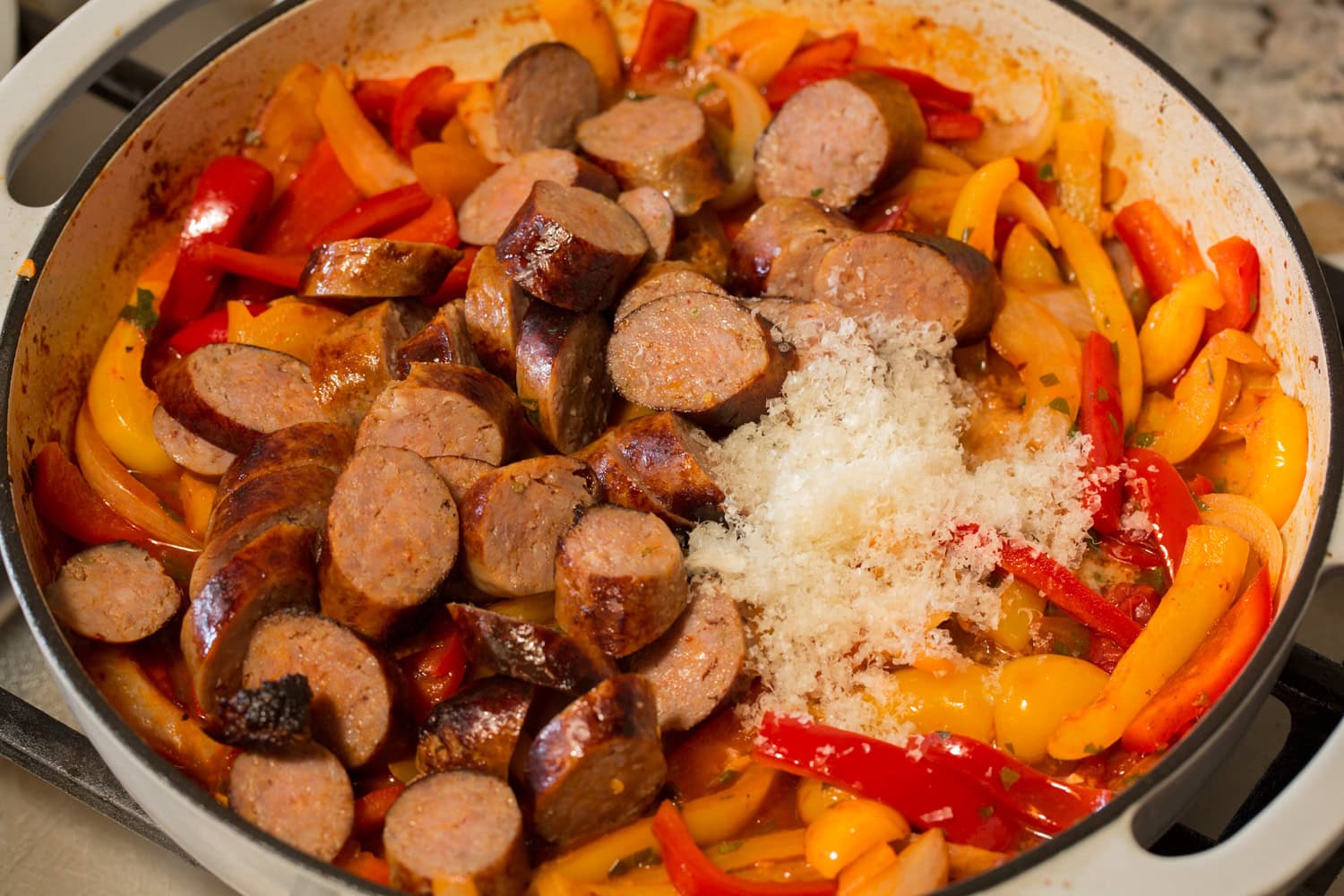 Italian sausages shown sliced into coins and to pan along with parmesan as the last step.