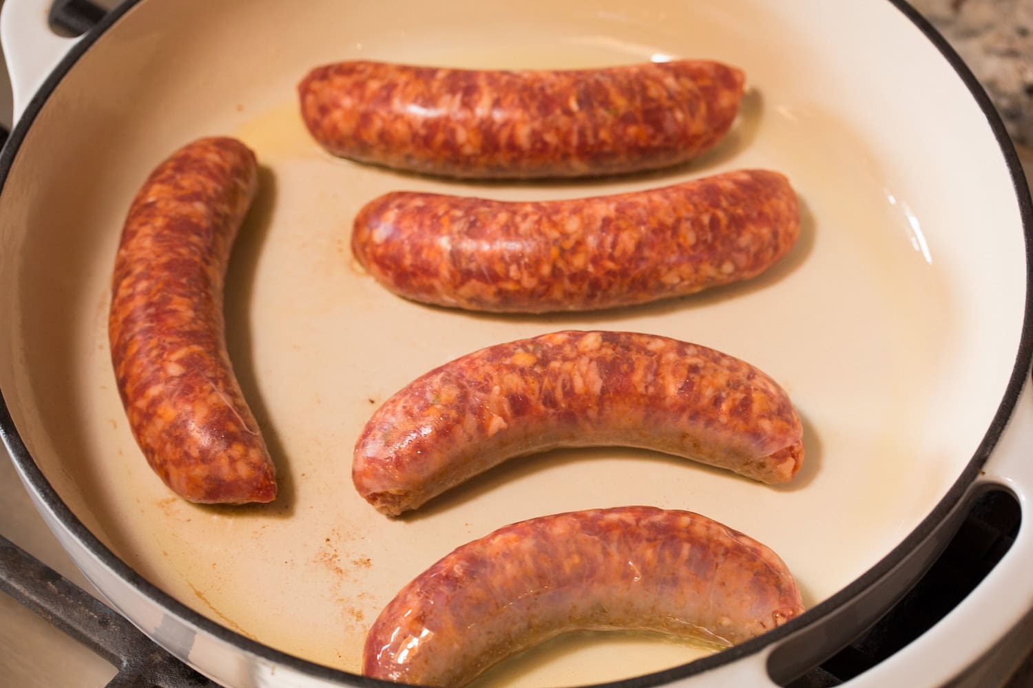 Italian sausage links shown in a skillet before cooking.